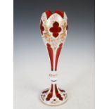 A late 19th century Bohemian white overlaid ruby glass vase, decorated with gilded foliage and