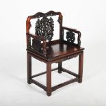 A Chinese dark wood armchair, late Qing Dynasty, the shaped top rail above a carved and pierced