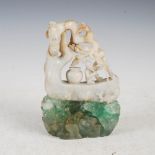 A Chinese jade carving on green polished and cut stone plinth, the jade carved and pierced with