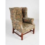 A George III style mahogany wing armchair, the floral upholstered back, arms and seat raised on