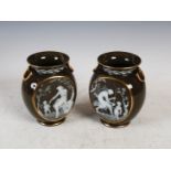 A pair of green ground pate-sur-pate urns, decorated with oval shaped panels of maidens and