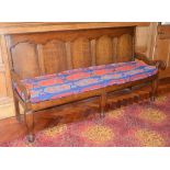 A George III oak settle, the five panelled rectangular back above a rectangular seat with loose