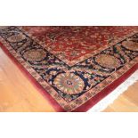 A large Persian carpet, 20th century, the madder ground decorated with foliate tendrils within a