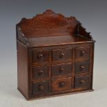 A 19th century stained pine miniature table top chest of nine drawers, with shaped three quarter