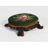 A 19th century rosewood foot stool, the oval shaped needlework upholstered top above a scroll carved