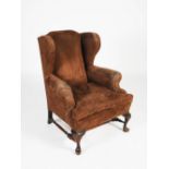 An early 20th century mahogany wing armchair, the brown suede upholstered back, arms and loose