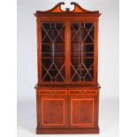 An Edwardian mahogany and satinwood banded bookcase, the moulded cornice with a broken scroll