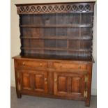 A 19th century oak dresser, the upright back with pierced frieze above three open plate racks, on