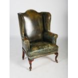 A 19th century oak and green leather upholstered wing armchair, with brass studded detail, raised on