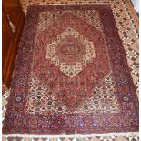 A Persian rug, 20th century, the ochre ground centred with a large floral medallion within a blue