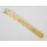 A Chinese ivory page turner, Qing Dynasty, the handle carved with mother and child, the blade carved