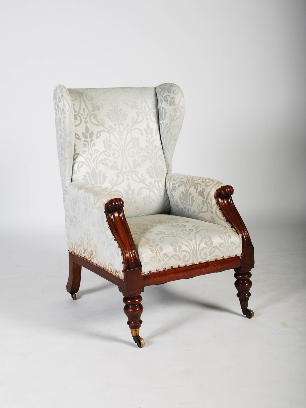 A 19th century mahogany wing armchair, the upholstered back, arms and seat raised on tapered