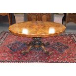 A Victorian walnut snap top loo table, the hinged oval top raised on a tapered cylindrical column
