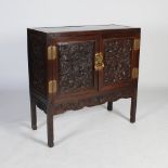 A Chinese dark wood side cabinet, late Qing Dynasty, the panelled rectangular top above a pair of