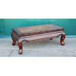 A Chinese dark wood low table, Qing Dynasty, the panelled rectangular top raised on four scroll