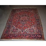 A Persian rug, 20th century, the rectangular madder ground field centred with a blue ground