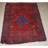 An Eastern madder ground rug, 20th century, the rectangular field centred with a blue ground