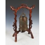 A Chinese bronze gong on carved dark wood stand, late 19th/early 20th century, the bell shaped