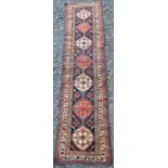 A Persian runner, 20th century, the rectangular blue ground centred with seven white and madder