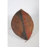A late 19th century African Tribal hide and wood shield, probably Maasai, decorated with red and