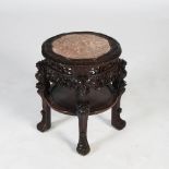 A Chinese dark wood urn stand, Qing Dynasty, the shaped circular top with a mottled red marble
