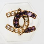 A 20th century split pearl and amethyst cabochon double horseshoe yellow metal ring, one horseshoe