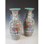 A pair of Chinese porcelain famille rose Canton twin handled vases, Qing Dynasty, decorated with