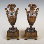 A pair of 19th century gilt metal and champleve enamel twin handled urns, raised on foliate cast