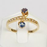 An early 20th century yellow metal, sapphire and pearl cross-over ring, with two pearl set hook