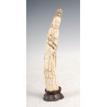A Chinese ivory figure of Guanyin, Qing Dynasty, carved standing holding a peach branch, on carved