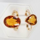 Two citrine and yellow metal rings, one set with oval facet cut citrine, the other set with a