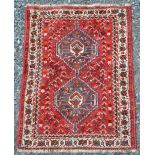 A Persian rug, 20th century, the madder ground decorated with two blue ground medallions within a