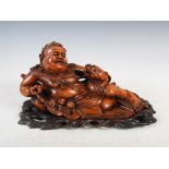 A Chinese carved wood figure of Liu Haichan, carved reclining with his three legged toad, with shell