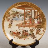 A Japanese Satsuma pottery plate, Meiji Period, decorated with children playing on a terrace, within