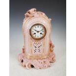 A late 19th century French pink ground porcelain mantel clock, the circular enamel dial with Roman