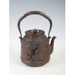 A Japanese iron tea pot, Tetsuvin, 19th century, the tapered cylindrical body cast in relief with