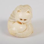 A Japanese ivory okimono of a cat, Meiji Period, with horn inlaid eyes, signed, 4.5cm high x 5cm