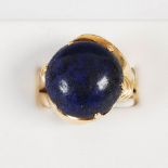 A lapis lazuli cabochon set yellow metal ring, with organic form shoulders and shank, gross weight