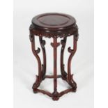 A Chinese dark wood urn stand, early 20th century, the circular top and scroll carved frieze