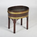 A George III mahogany and brass bound wine cooler, the oval shaped wine cooler with a lead lined