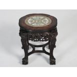 A Chinese dark wood jardiniere stand, Qing Dynasty, the shaped circular top centred with a famille