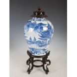 A Chinese porcelain blue and white jar, pierced wood cover and stand, Qing Dynasty, decorated with