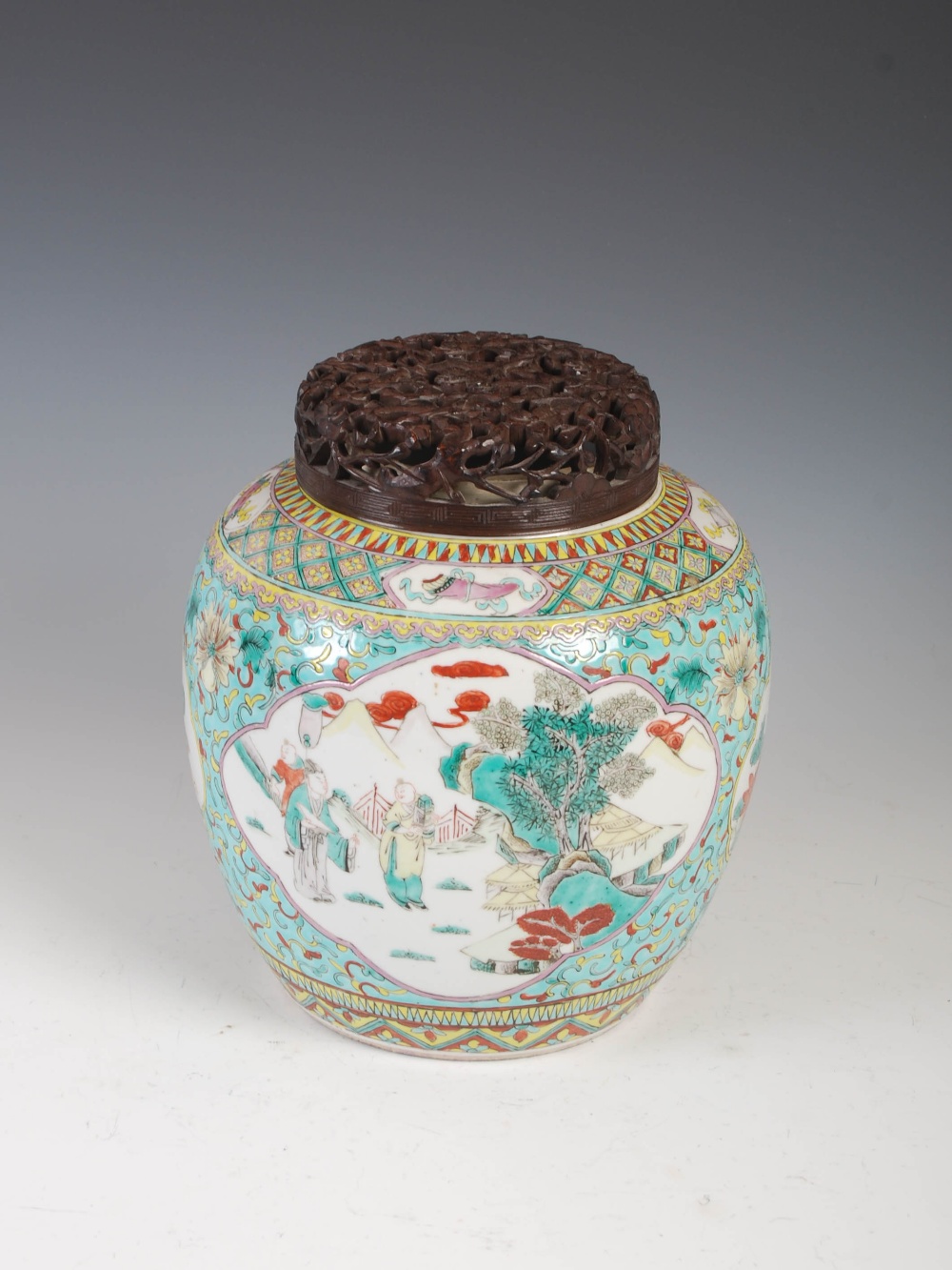 A Chinese porcelain famille verte green ground jar and pierced wood cover, Qing Dynasty, decorated