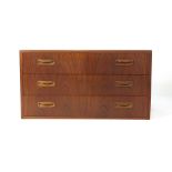 A 1970's teak chest of three drawers on circular feet, w.