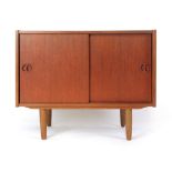 A 1970's teak cabinet with two sliding doors on circular legs, w.