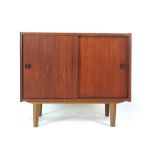 A 1970's teak cabinet with two sliding doors on circular legs, w.