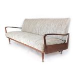 A 1970's teak framed daybed with cream speckled upholstery, the arms of organic form,