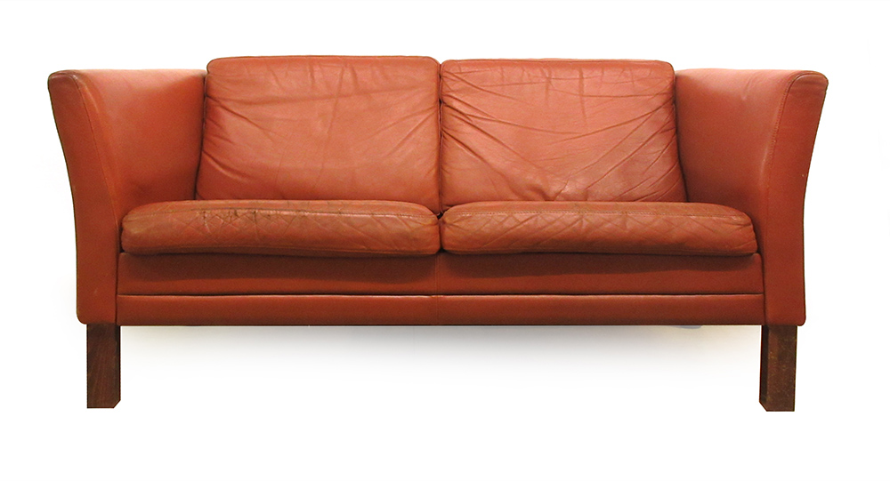 A 1970's red leather two seater sofa on stained beech legs CONDITION REPORT: Wear.