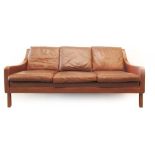 A 1970's wine coloured three seater sofa on mahogany feet