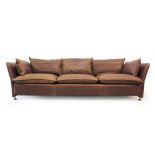 A 1970's brown leather three seater sofa with loose cushions on chromed feet and castors